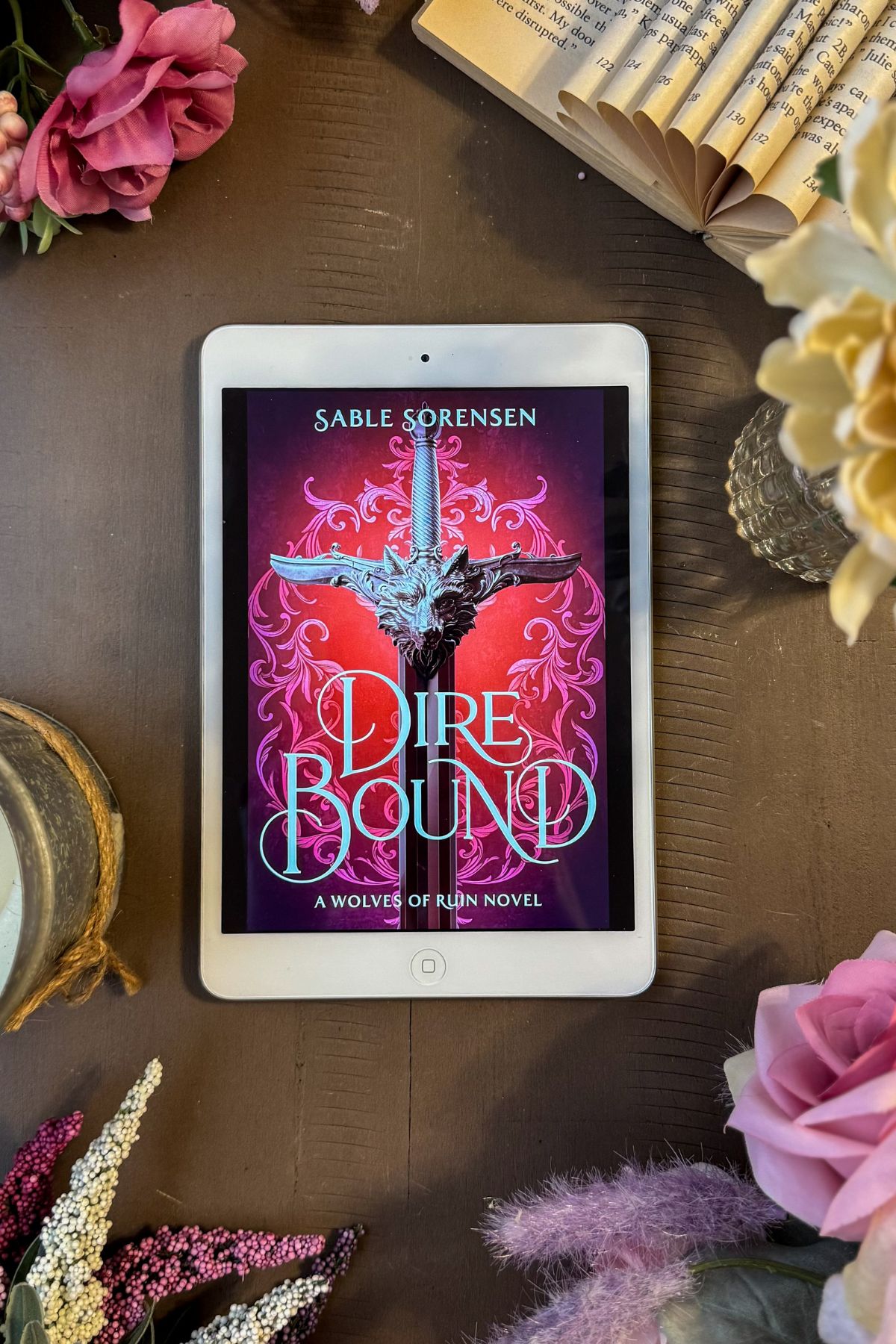 Dire Bound book flat lay with flowers and an old book.