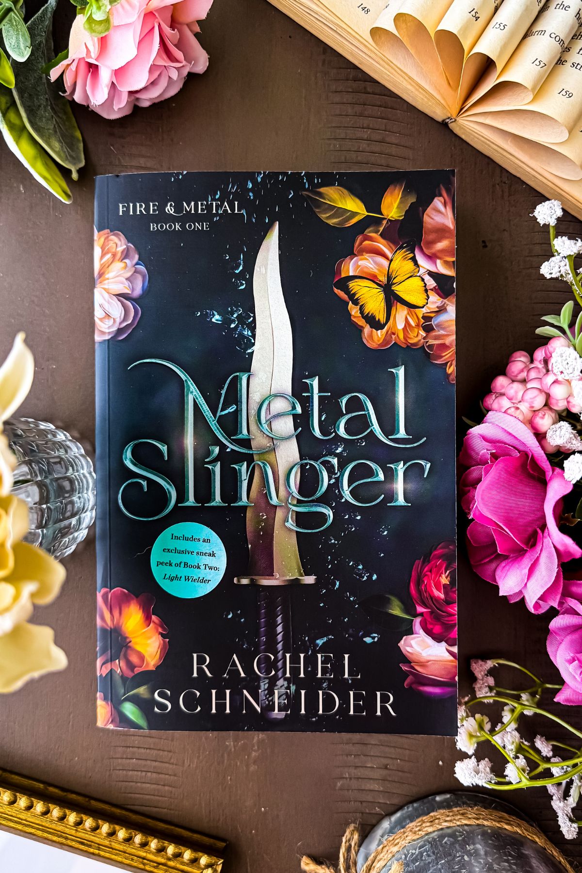 metal slinger book flat lay with flowers and candles.