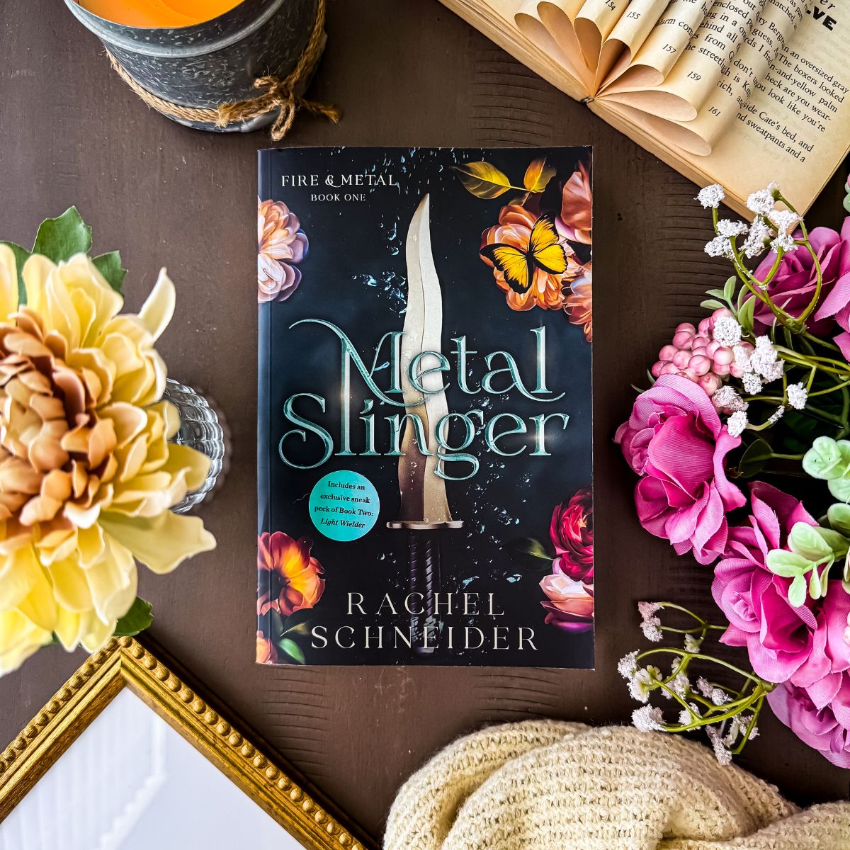 metal slinger book flat lay with flowers and candles.