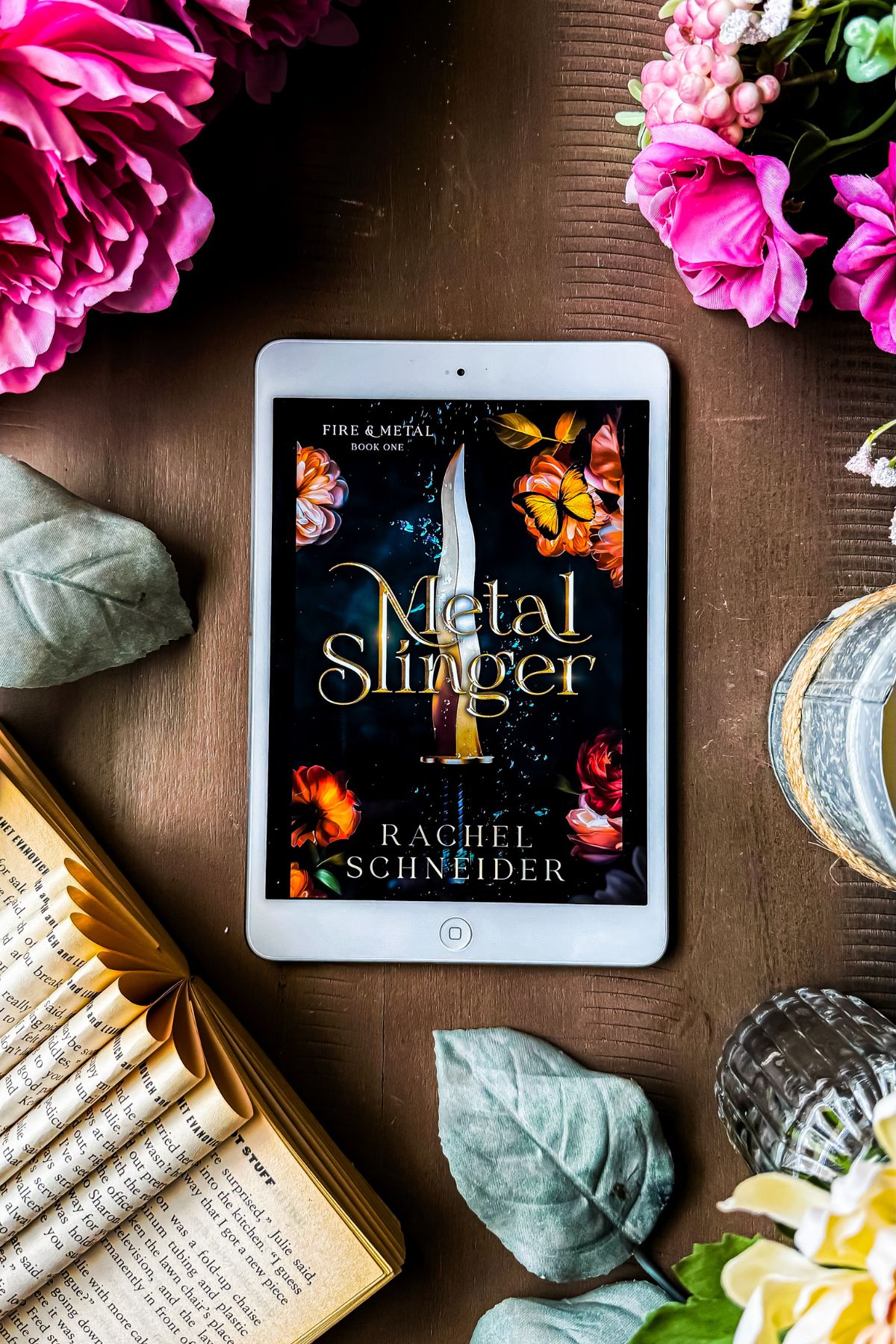 metal slinger book flat lay with flowers and candles.