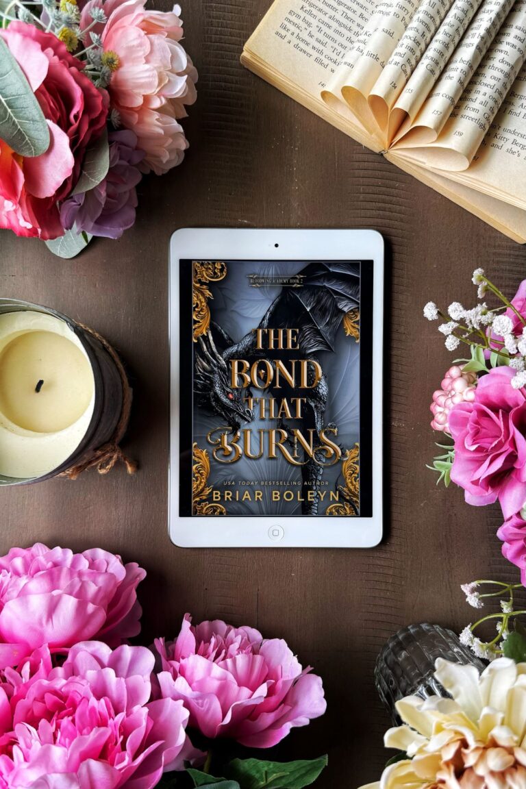 The Bond That Burns book on an iPad flat lay with flowers and an open book