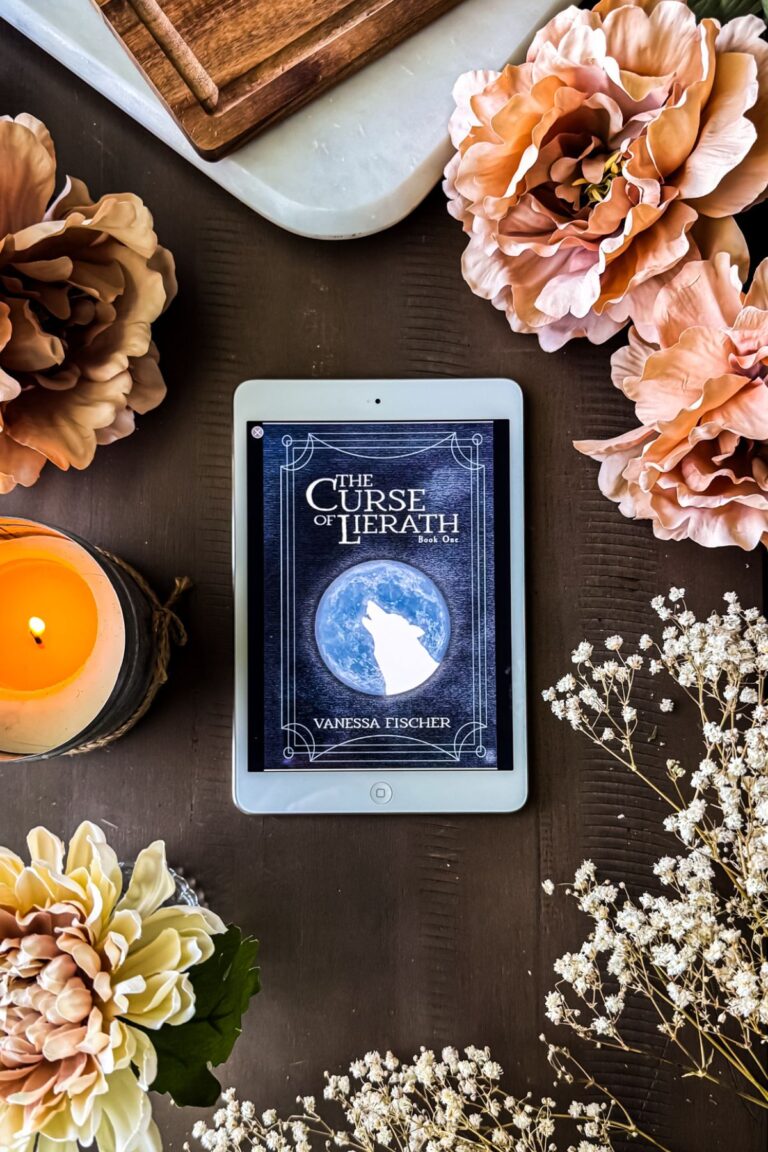 The Curse of Lierath on an iPad with flowers.