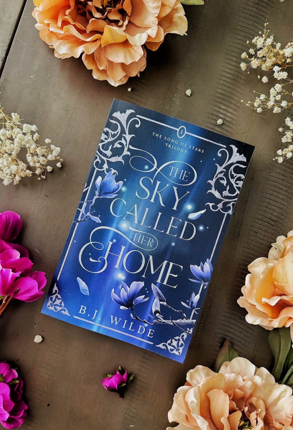 the sky called her home book flay lay with flowers.