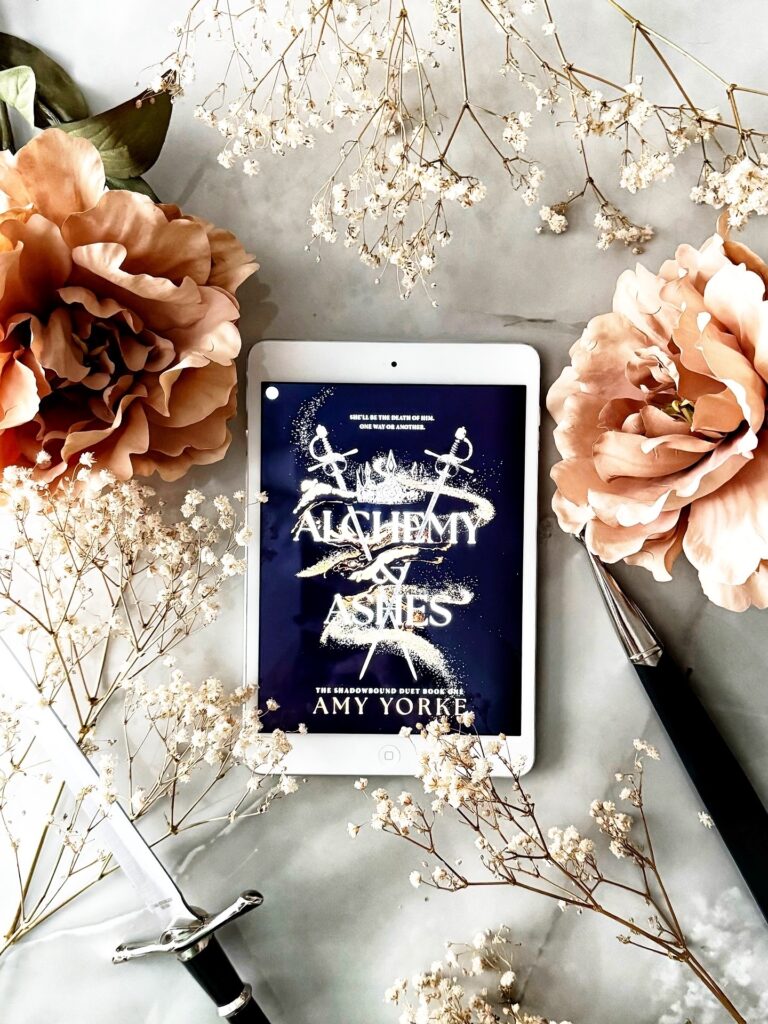 alchemy & ashes on iPad surrounded by flowers