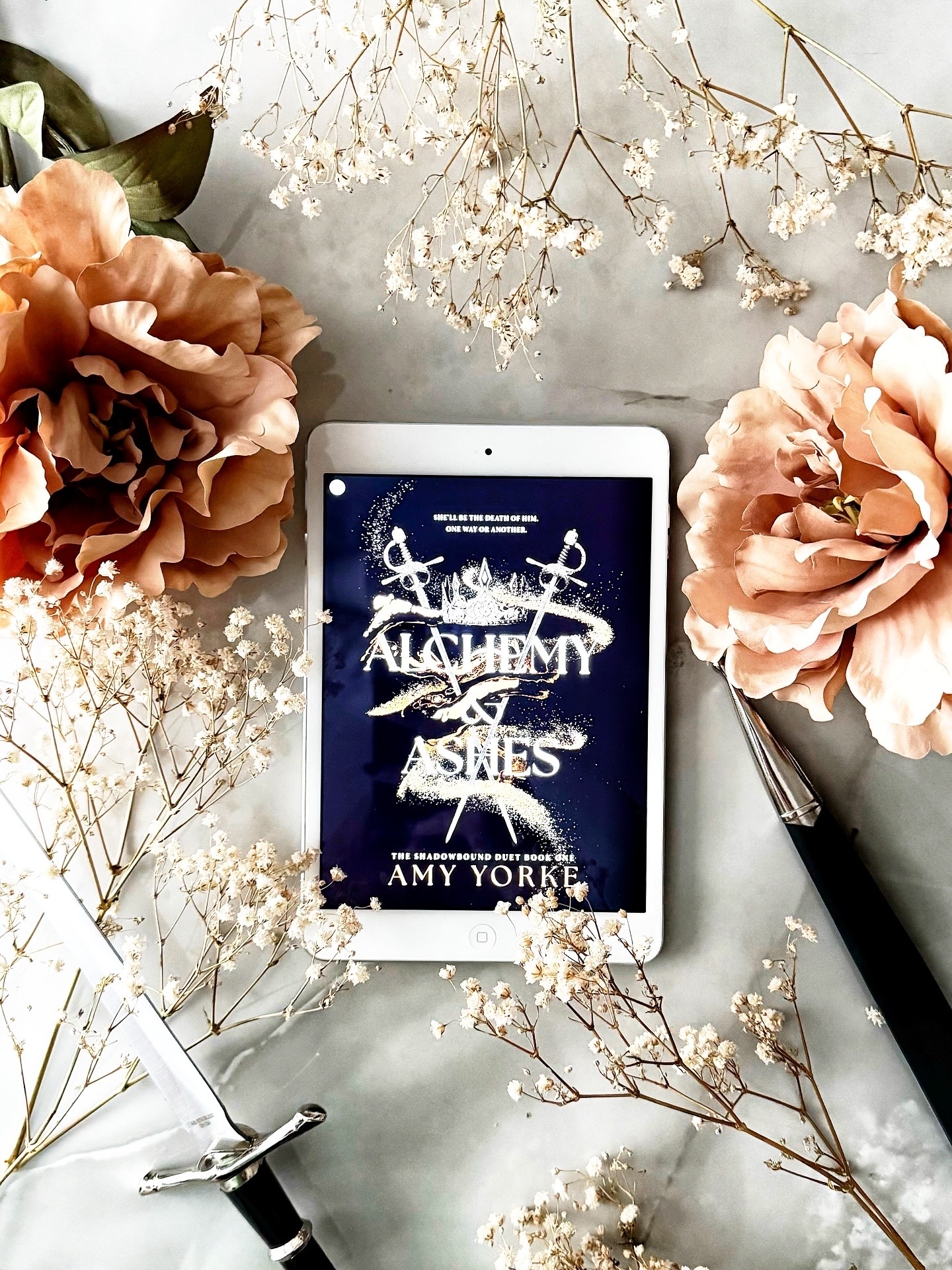 alchemy & ashes on iPad surrounded by flowers